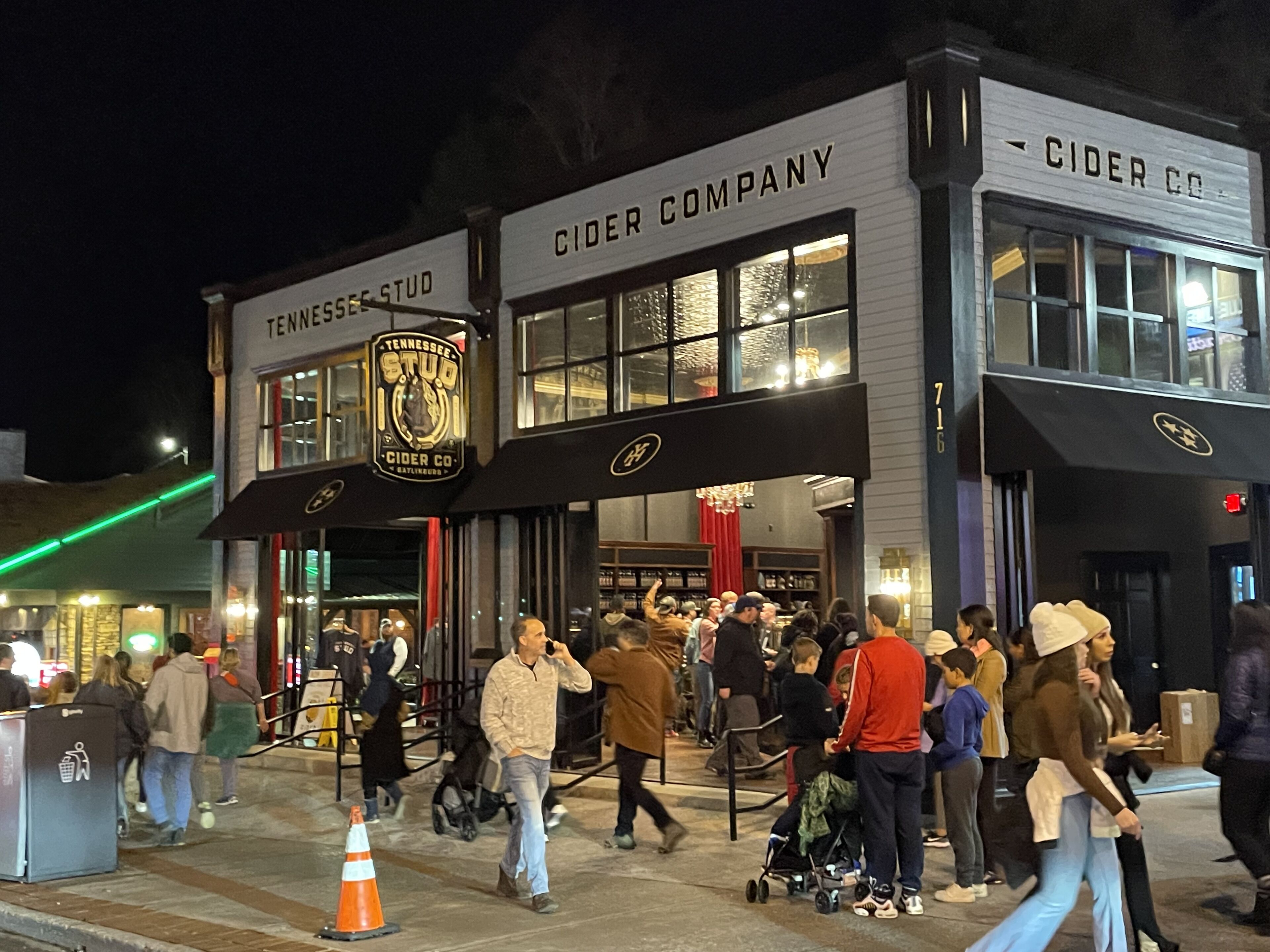 A building with signage for 'Tennessee Studio Cider Co.' and 'Cider Co.' with a crowd of people outside.