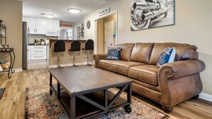 A living room with a brown leather couch, a wooden coffee table, and a patterned rug.