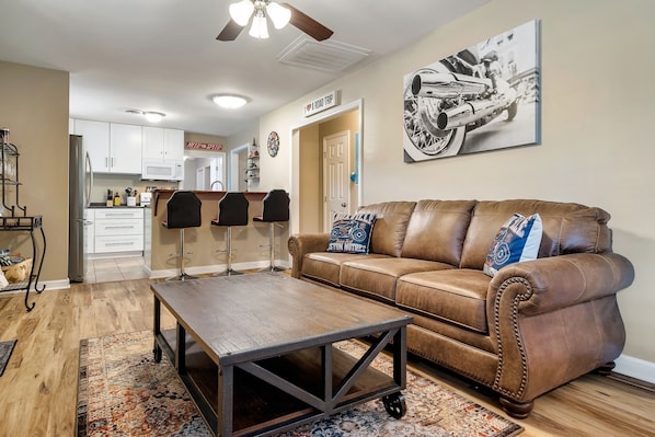 A living room with a brown leather couch, a wooden coffee table, and a patterned rug.