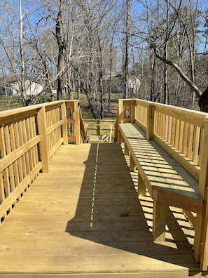 A wooden bridge with benches, surrounded by trees.