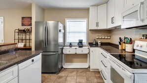 A modern kitchen with white cabinets, stainless steel appliances, and a granite countertop.