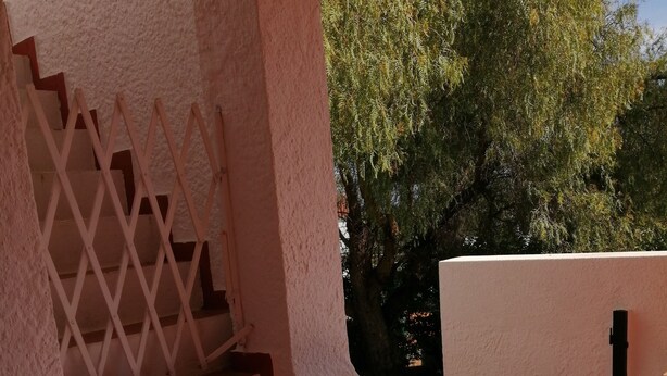 Una scala esterna con ringhiera bianca che conduce a una terrazza con piastrelle in terracotta.