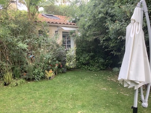 Ein Garten mit Rasen, einem weißen Sonnenschirm und einem Haus mit Ziegeldach.