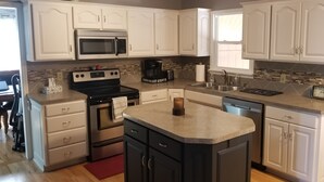 A modern kitchen with white cabinets, a granite countertop, a built-in oven, a microwave, a coffee maker, and a dishwasher.