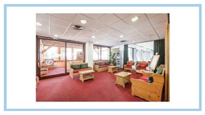 Ein Zimmer mit Holzmöbeln, einem roten Teppich und großen Fenstern.