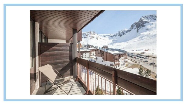 Ein Balkon mit Blick auf einen verschneiten Berg und einen Parkplatz.
