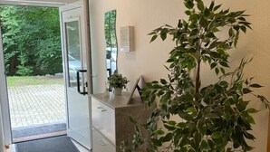 A reception area with a glass door leading outside, a potted plant, and a small desk with a computer. - Holiday apartment at Ohrensbächle (Glottertal)
