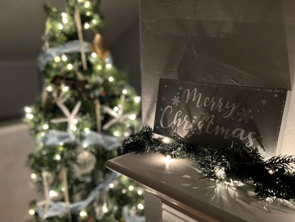 A Christmas tree with lights and a sign that reads "Merry Christmas" on a wall.