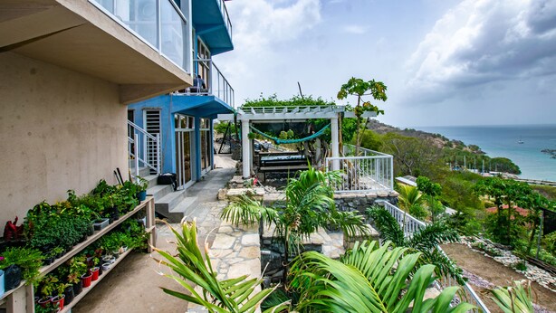 Un balcon avec vue sur la mer, des plantes en pot et un hamac.