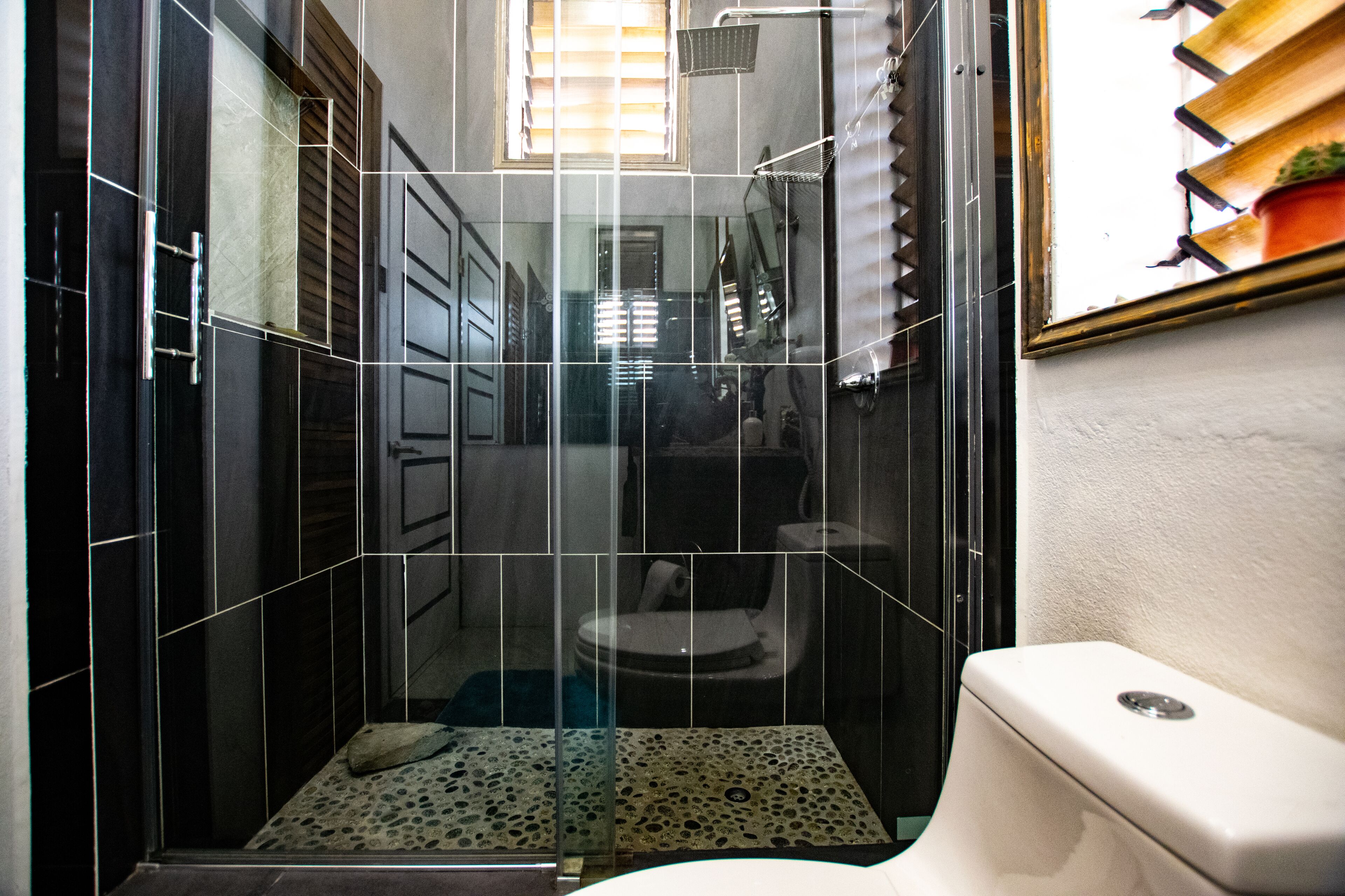 Een badkamer met glazen wand, toilet en douchehoek.