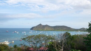 Une vue sur la côte, avec des bateaux, une montagne et une zone boisée.