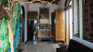 Une cuisine spacieuse dotée de meubles en bois, d’un réfrigérateur et d’un grand îlot central. On y trouve également un coin repas avec un banc et un mur décoratif.