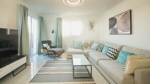 En moderne stue med sofa, sofabord, fjernsyn og lænestol.