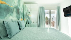 Et hotelværelse med en stor seng, et spejl, et fjernsyn og en balkon med udsigt.