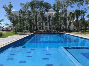 Une piscine rectangulaire aux carreaux bleus, entourée d’une terrasse également carrelée.