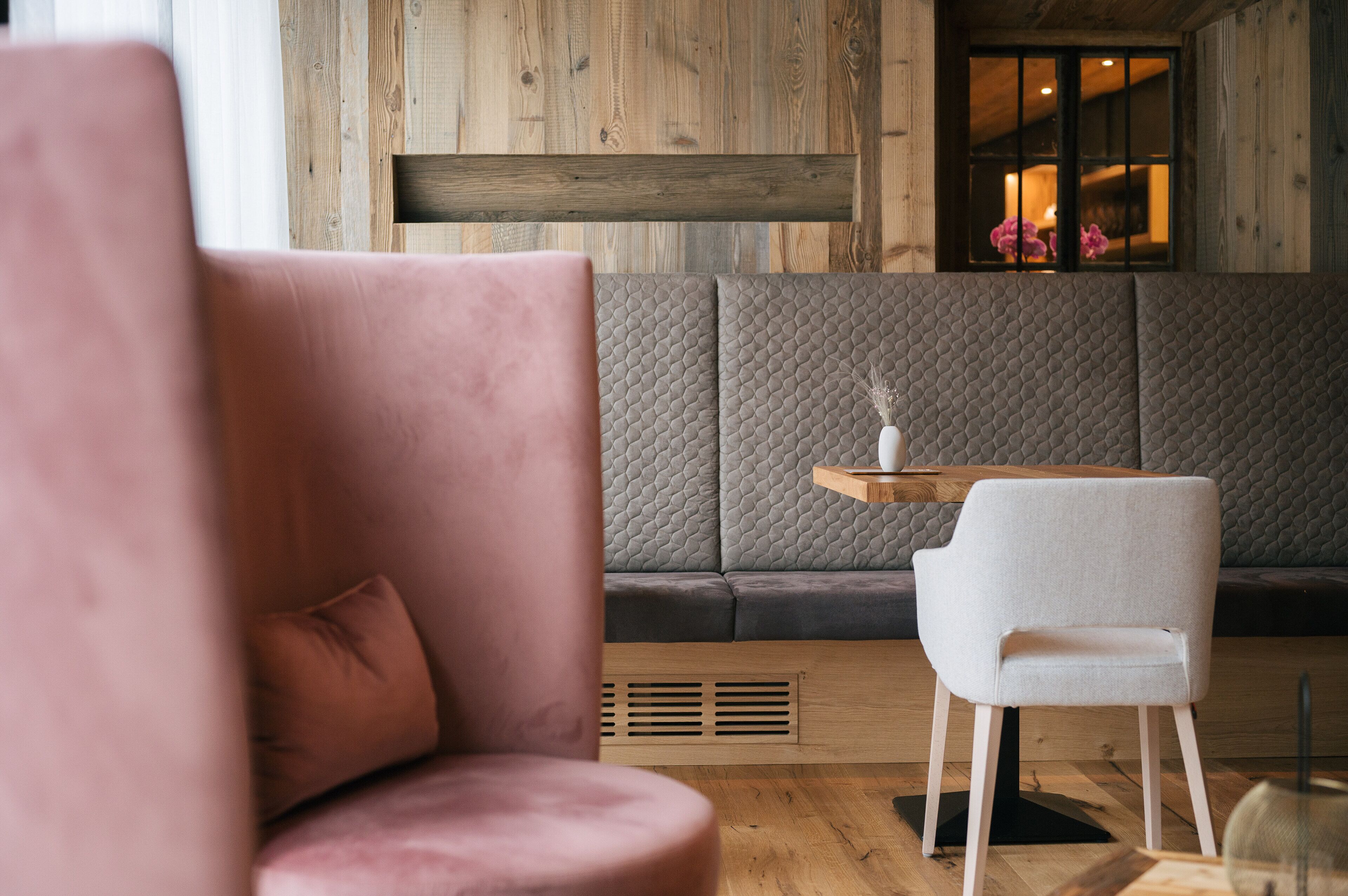 A modern interior with a wooden wall, a cushioned bench, and a white chair.