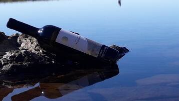 A telescope on a rock by a calm lake with a person in the distance.