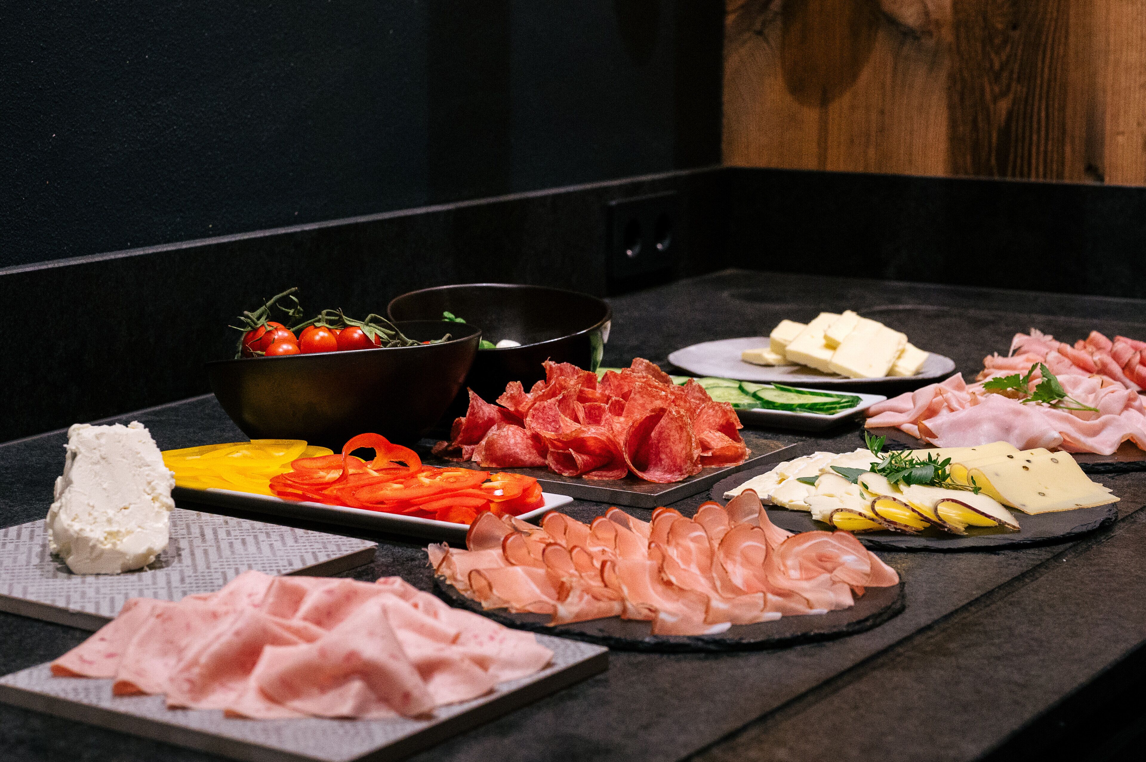 Diversos alimentos, incluindo queijo, carnes e vegetais, dispostos sobre uma mesa.