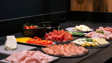 Diversos alimentos, incluindo queijo, carnes e vegetais, dispostos sobre uma mesa.