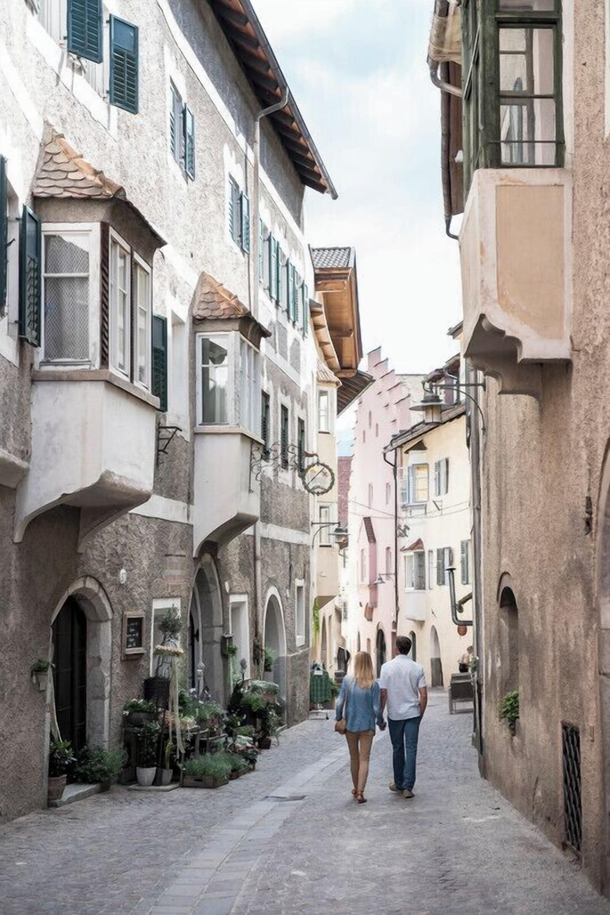 Eine schmale Straße gesäumt von historischen Gebäuden, mit Balkonen und Rundbogenportalen.