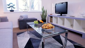 Relax in this stylish living room with a comfortable sofa, flat-screen TV, and a view of the surrounding trees.