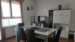 Una cocina moderna con comedor, que incluye un televisor, armarios y un reloj en la pared.