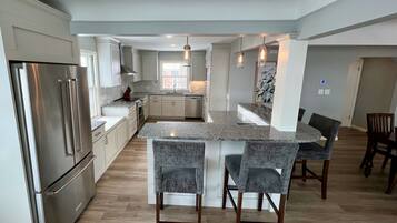 Una cocina moderna con una isla central, electrodomésticos de acero inoxidable y una zona de comedor con taburetes de bar.