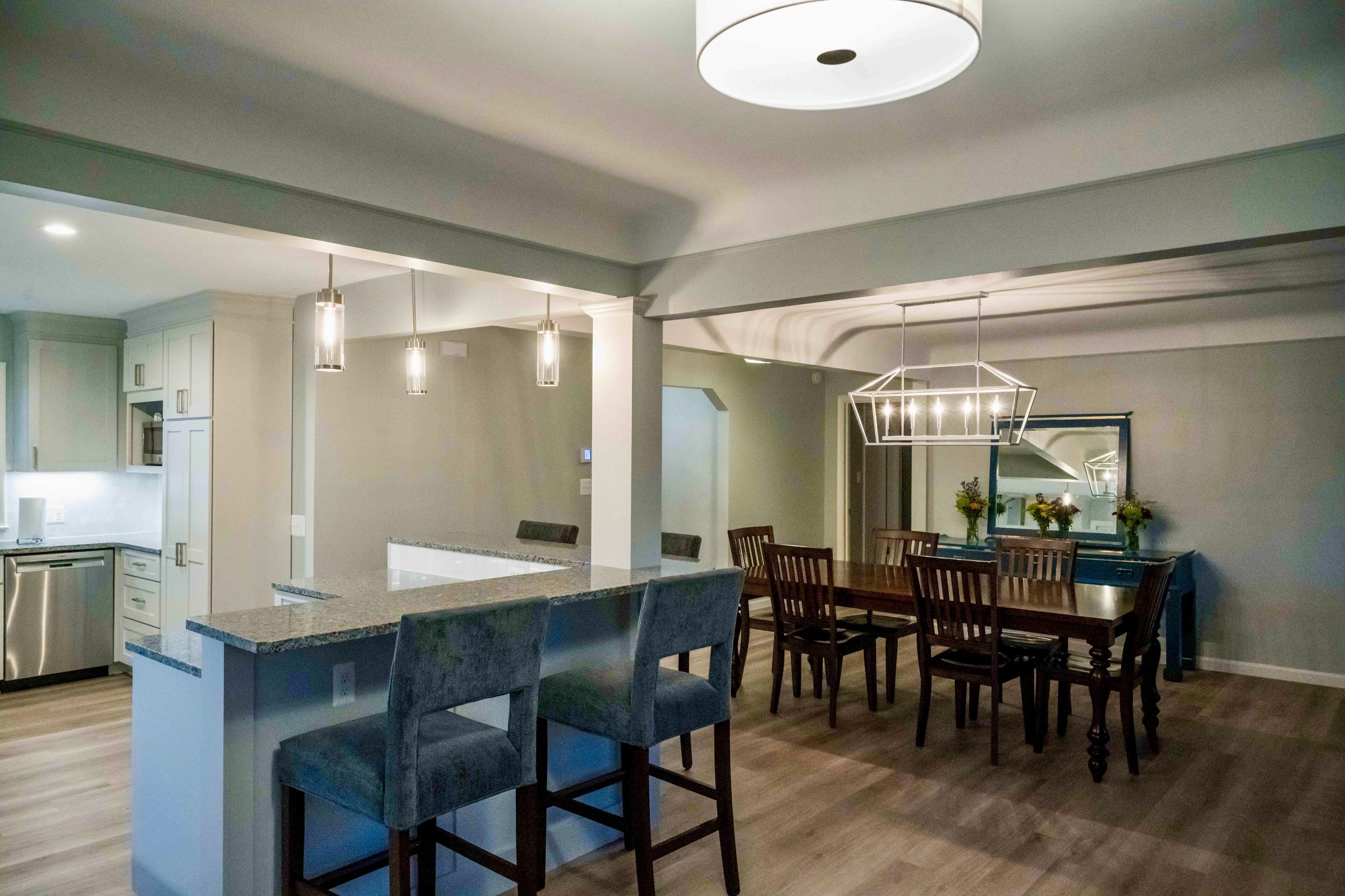Una cocina moderna con una isla central, taburetes de bar e iluminación colgante.