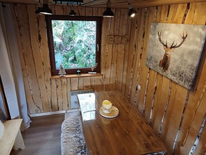 Et træpanelt interiør med et vindue, et billede af et dådyrshoved og et bord med en kop.