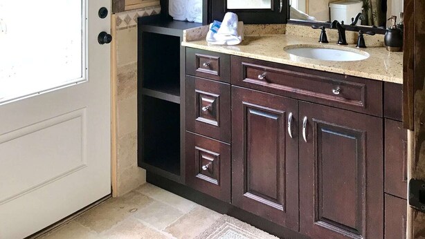 Une salle de bain avec un plafond en bois, un grand miroir, un lavabo et des meubles de rangement en bois foncé.