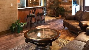 Un intérieur rustique avec un plafond en bois, un coin bar, des sièges en cuir et un grand téléviseur à écran plat.