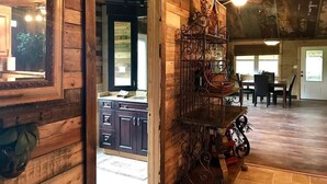 Un intérieur rustique en bois, comprenant un coin cuisine, une table à manger avec des chaises et une étagère décorative en métal.