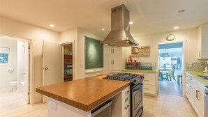 A modern kitchen with a central island, built-in oven, and stainless steel range hood.