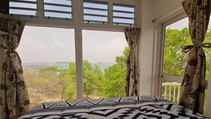 Een slaapkamer met een groot raam, een bed met behang en gordijnen.