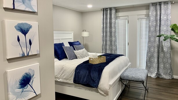 A modern bedroom with a bed, bedside table, and artwork on the wall.