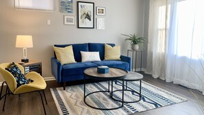 A living room with a blue sofa, yellow armchair, and a round coffee table.