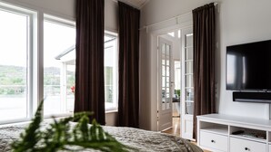 A bedroom with a bed, a TV, a wardrobe, and a view of the outdoors. - Exclusive house with private boathouse (Västra Götalands län)