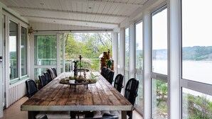 A large wooden table with chairs, a decorative centerpiece, and a view of a lake through large windows. - Exclusive house with private boathouse (Västra Götalands län)