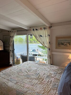 A bedroom with a large bed, a view of a lake, and a dining area with outdoor seating.