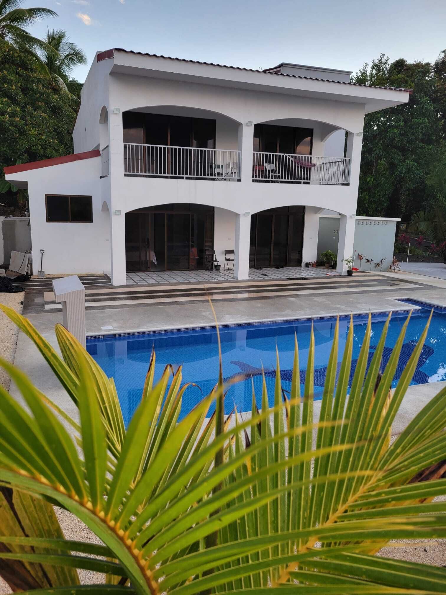 Una casa blanca de dos pisos con una piscina al frente.