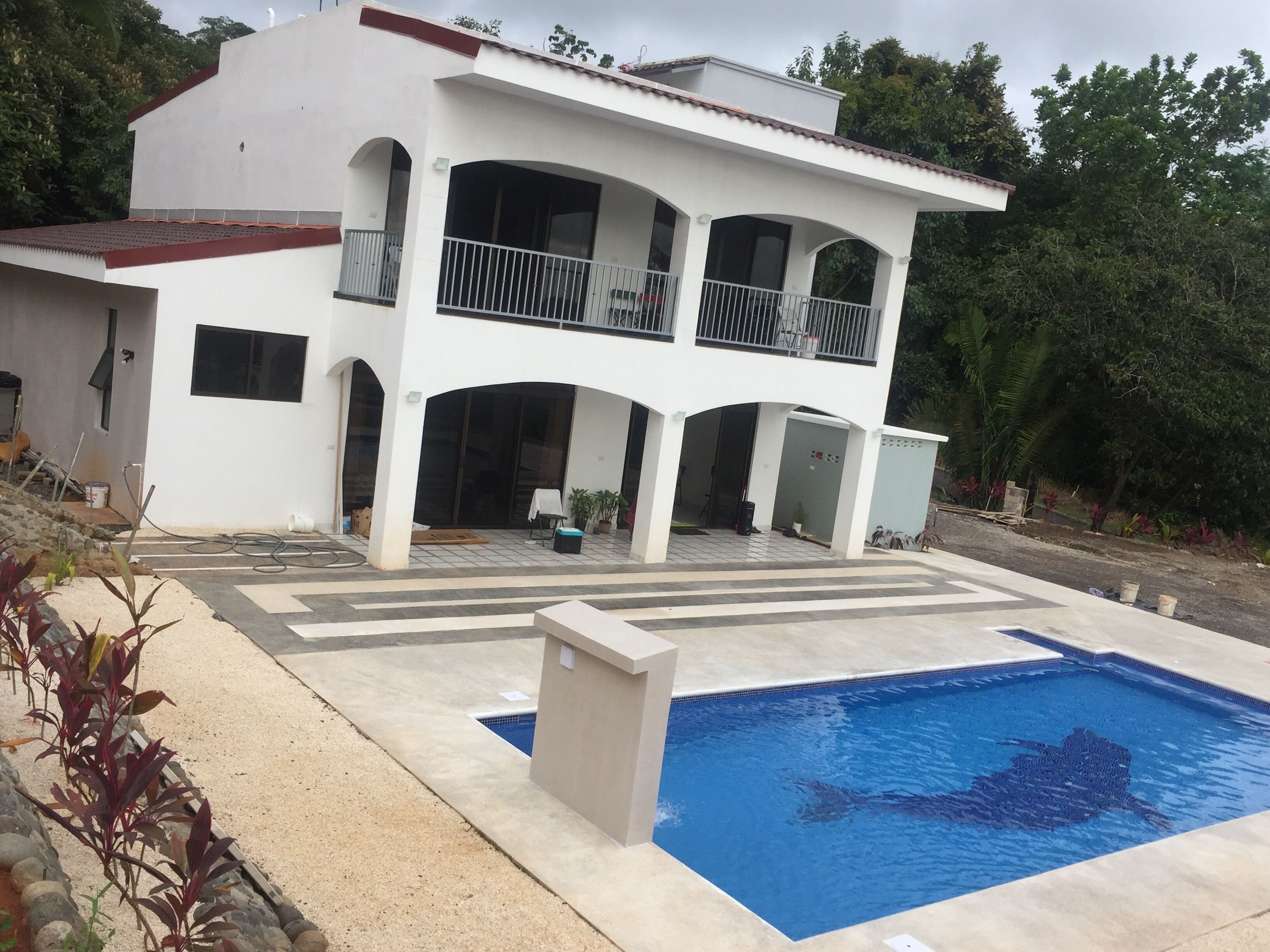 A two-story house with a swimming pool, a balcony, and a covered patio area.