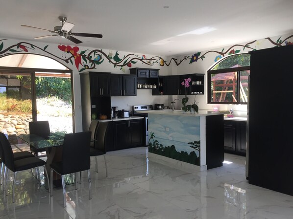 A modern kitchen with dark cabinets, a central island, and a ceiling fan.