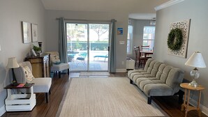 A living room with a sofa, armchairs, a coffee table, and a rug. There is a sliding glass door leading to a patio area. - Quiet Family Friendly Saltwater Pool Home, Near Beach (Navarre)