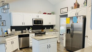 A modern kitchen with white cabinetry, a stainless steel refrigerator, a microwave, and a stove. - Quiet Family Friendly Saltwater Pool Home, Near Beach (Navarre)