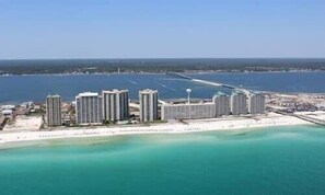 Um hotel costeiro com vários edifícios altos, uma praia em primeiro plano e uma vista desimpedida do oceano.