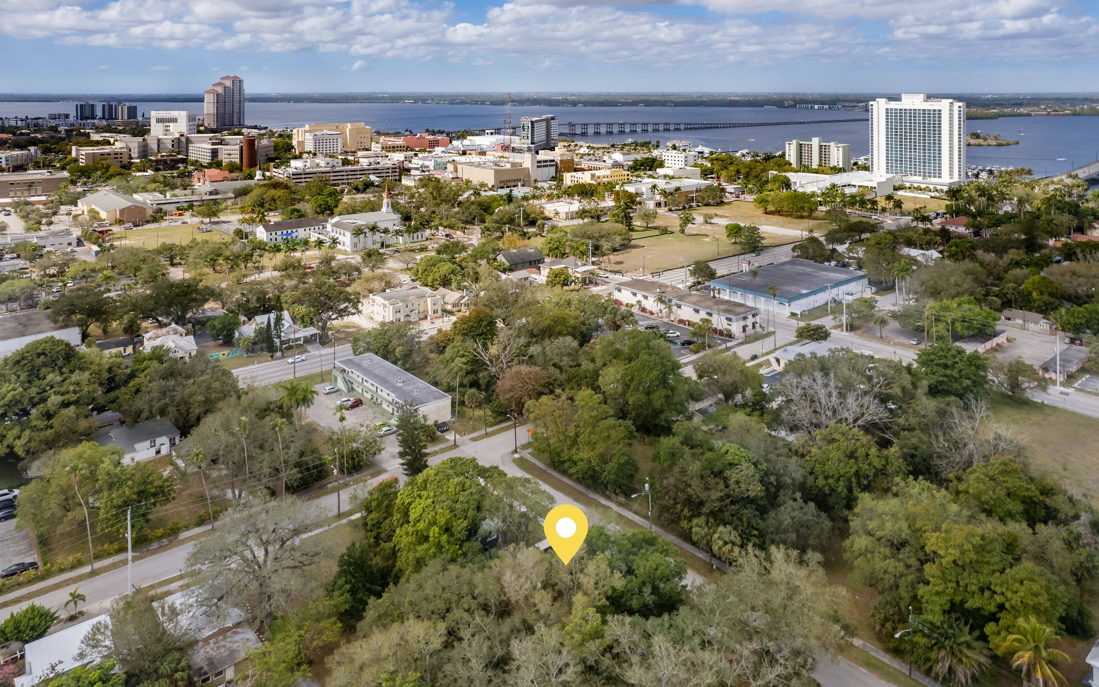 An aerial view of a coastal city with a mix of residential and commercial buildings, a prominent bridge, and a marina.