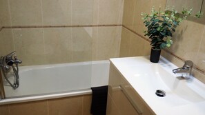 A bathroom with a bathtub, a sink, a potted plant, and a towel rack. - Apartment in the Old Town of Ourense **** Solaina das Burgas **** (Ourense)