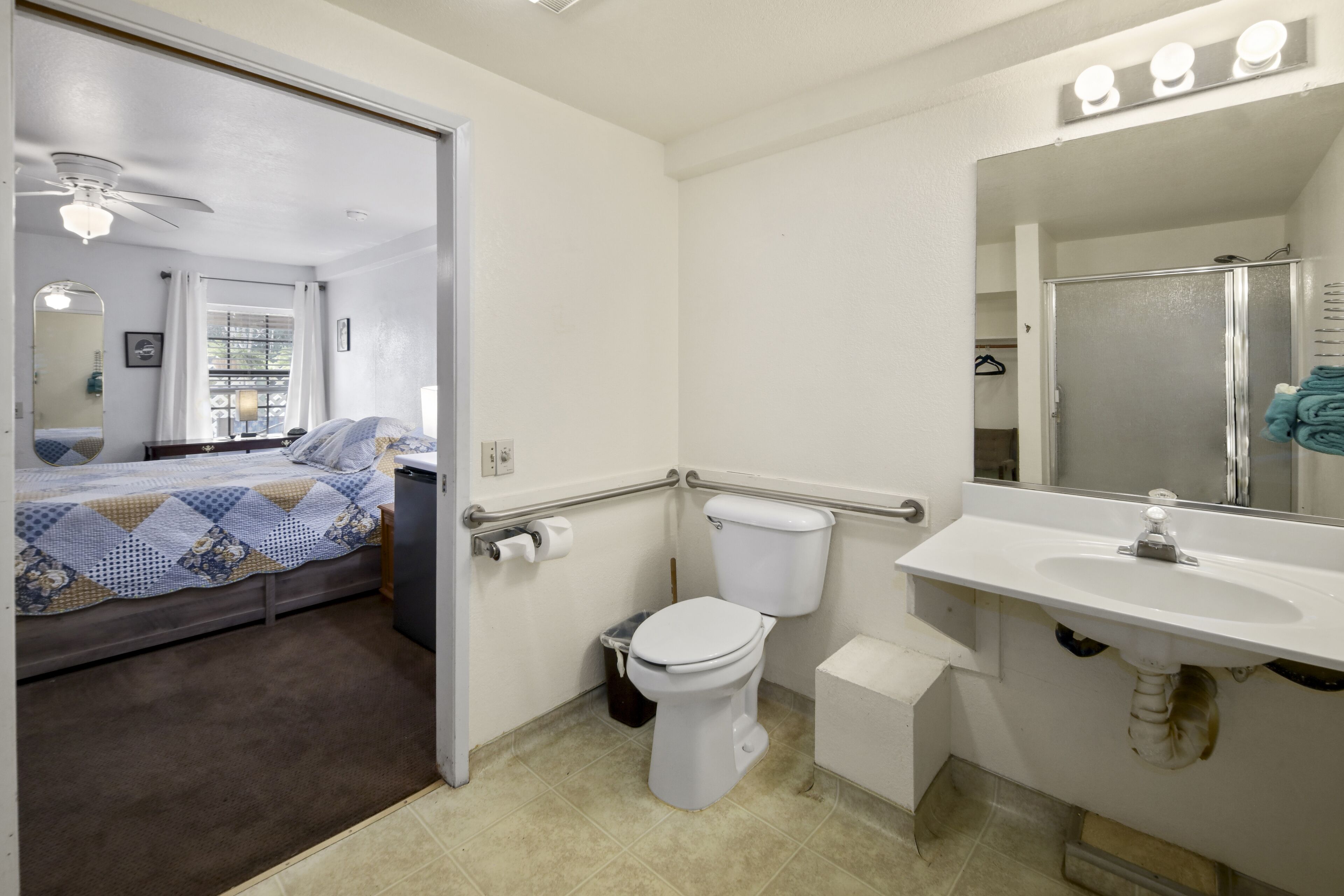 A bathroom with a toilet, sink, and mirror.