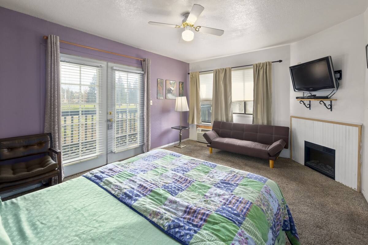 Een hotelkamer met een bed, een slaapbank, een televisie en een open haard.