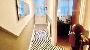 Ein Korridor mit Schachbrettfußboden, einer weißen Tür mit Glasfeldern und einem hölzernen Türrahmen.